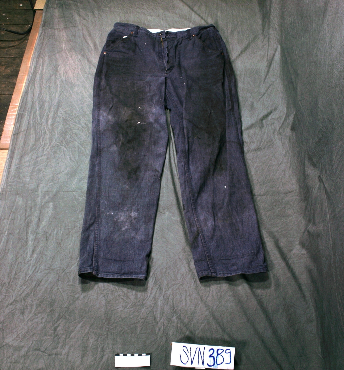 Jeansbukse, 5 lommer, i mørkeblåttj eansstoff, brun detaljsøm.Stor mørk flekk på baksiden av det ene buksebenet.

