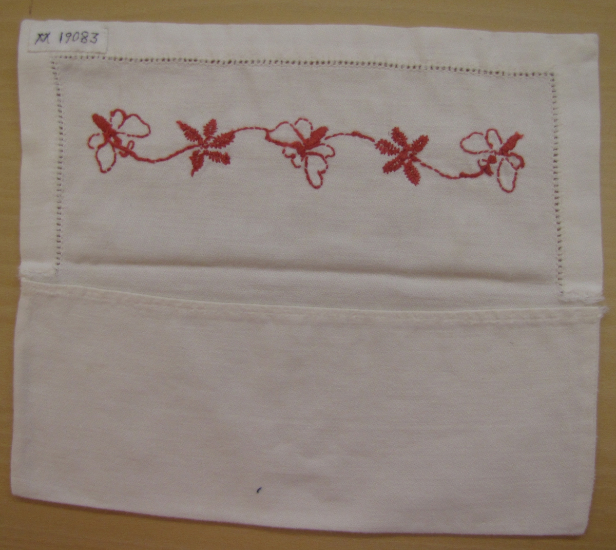 Väska för servett. Troligen tillhört någon av givarens mostrar (födda på 1890-talet).

Broderi i rött, fjärilar och blommor. Hålsöm runt kanten.