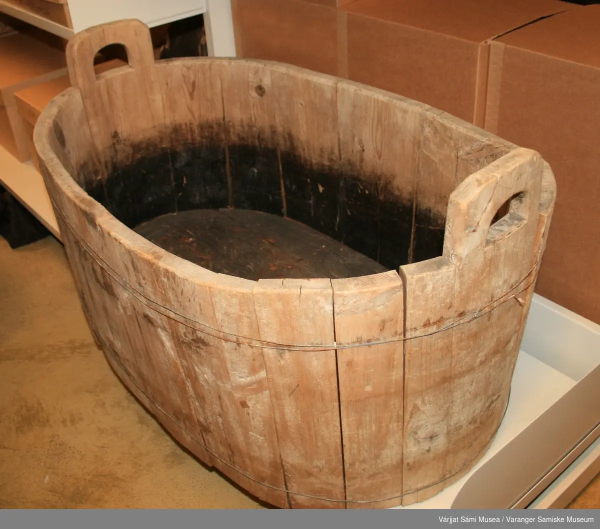 Oval badestamp av tre med håndtak i kortsidene, består av trestaver som holdes sammen av streng.