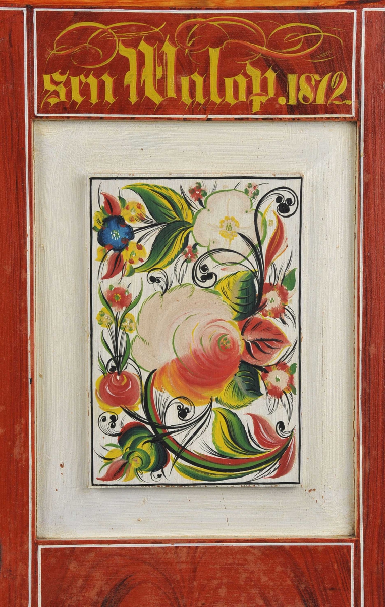 På rød eikebunn (ådring) med rosefelt i kvitt: rosemåla i rødt, gult, grønt og svart. Innvedig er det marmor imitasjon i blått og ein utskoren bord som er måla gul.