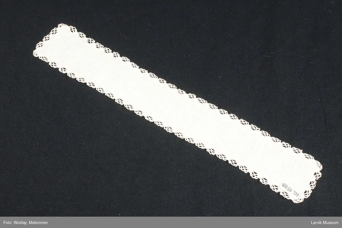 Form: hvitt,hardt tvunnet bomullsgarn, håndstrikket i rette masker frem og tilbake ca. 9 r m pr. cm., helt rundt en heklet bord av tagger i faste masker med nettverk av luftmasker i mellom
