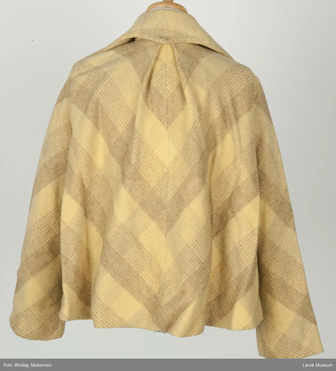 Kort jakke med krave, lommer og lange ermer. Ruter i gule og lyse brune farger.