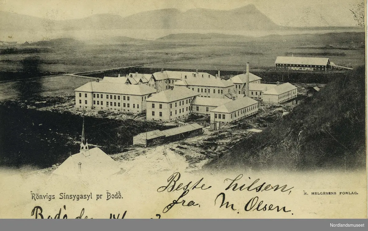 Postkort med bilde av Rønvik Sinnsykeasyl i Bodø. Bygningskomplekset er omgitt av åkerland og åpne jorder.

Bakside: Grønt postfrimerke, posthorn, 5 øre. Stemplet Nordlands postexp, 15.10.1909.