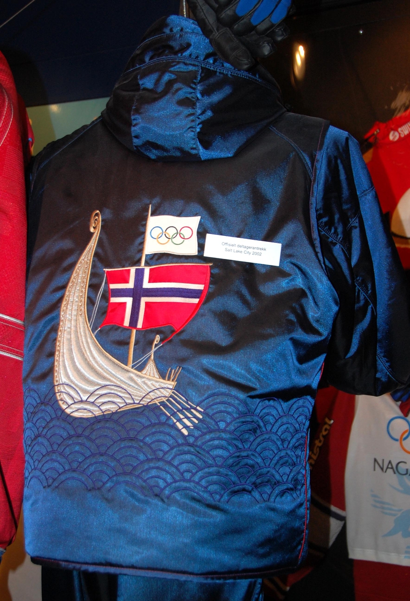 Blå vest med motiv på ryggen av et vikingskip med et norsk og et olympisk flagg på masten.