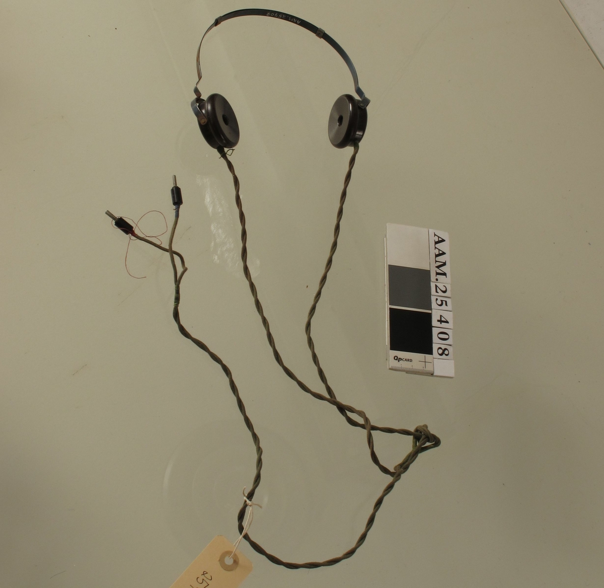 To runde øretelefoner montert på bøyle, ledning. Hørte til radio som ble brukt til illegal lytting av "gutta på skauen" når de lå og ventet på slipp.