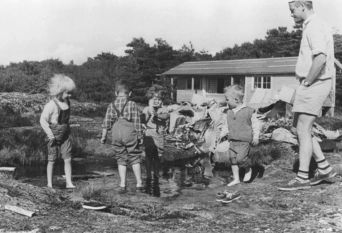 Barn leker i damm utenfor nybygd hytte.