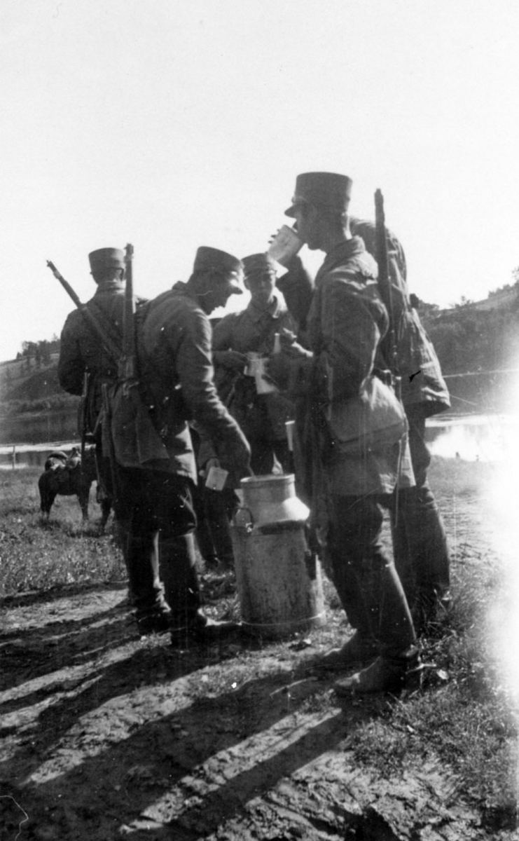 Soldater i rideantrekk.Pause med å drikke melk fra melkespann.
