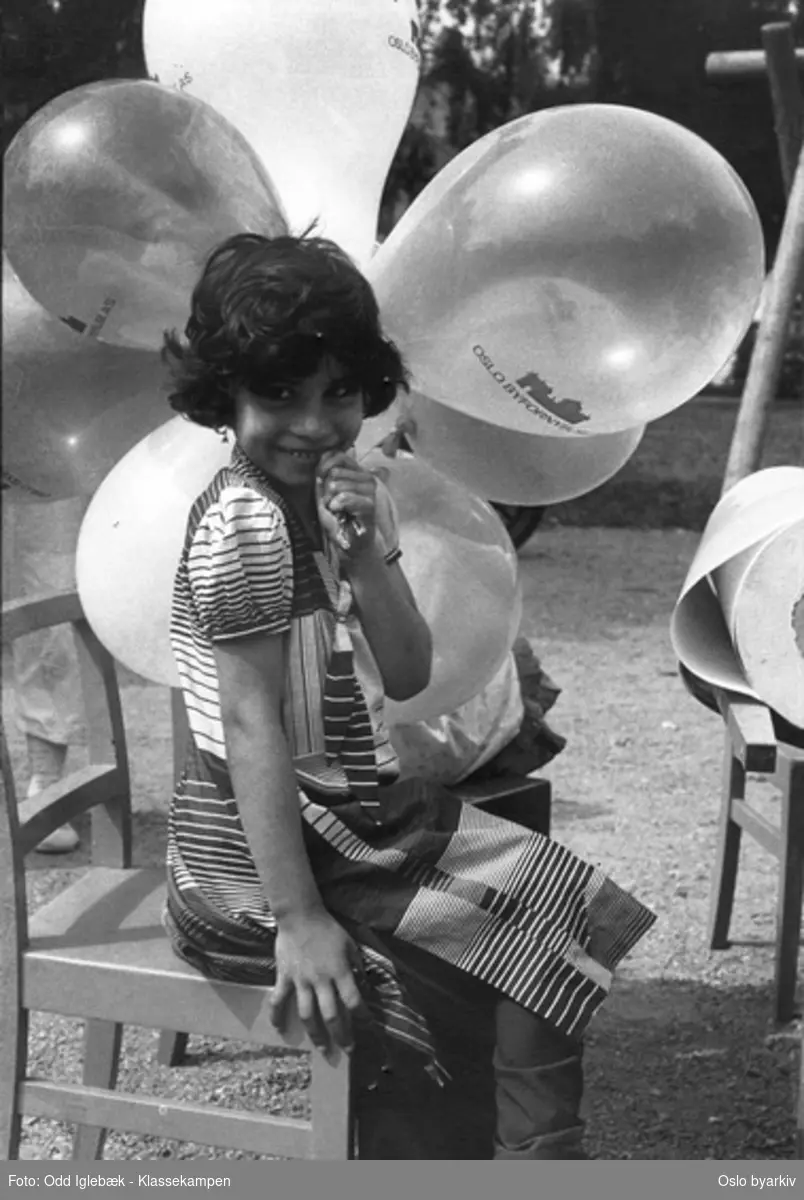 Jente som sitter på en stol med ballonger påtrykket OSLO BYFORNYELSE AS.