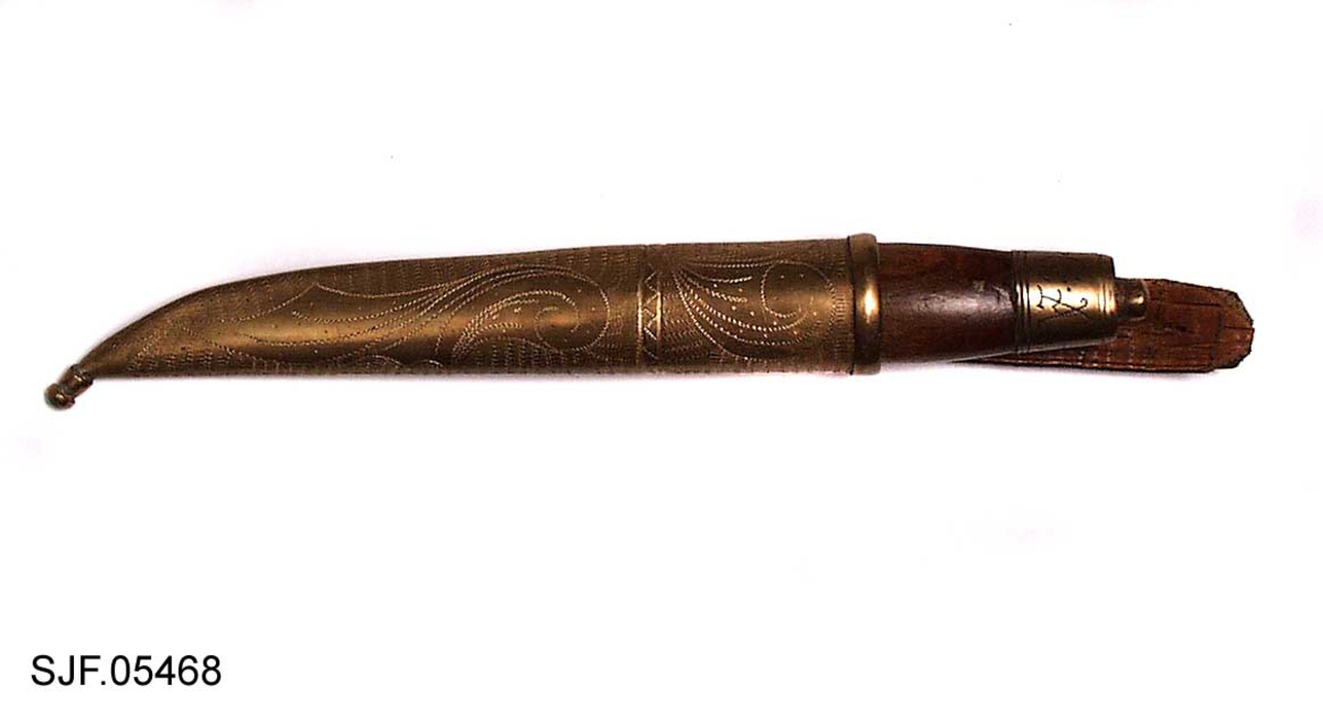 Kniven har brunbeiset skaft, antageligvis av bjørk. Slire og holker er av messing. Slira er foret med papp. Hempa er av imitert krokodilleskinn. Kniven er innkjøpt sammen med andre kniver i ei samling fra Birger Arntzen. 
