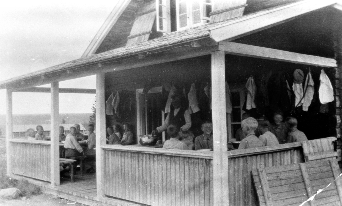 Gutter fra Toftes Gave, Nedre Sund, Helgøya på ferie på Aursmoen seter. Spiser mat på verandaen.
