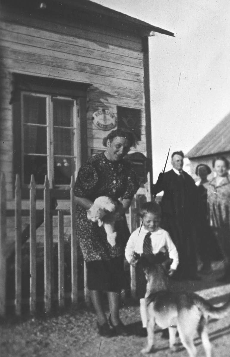 Folk og hund utenfor Skallelv Postkontor. Damen er Olga Sundelin og gutten Haldor Sundelin. Man bak i dress er Osvald Emanuel Sundelin.