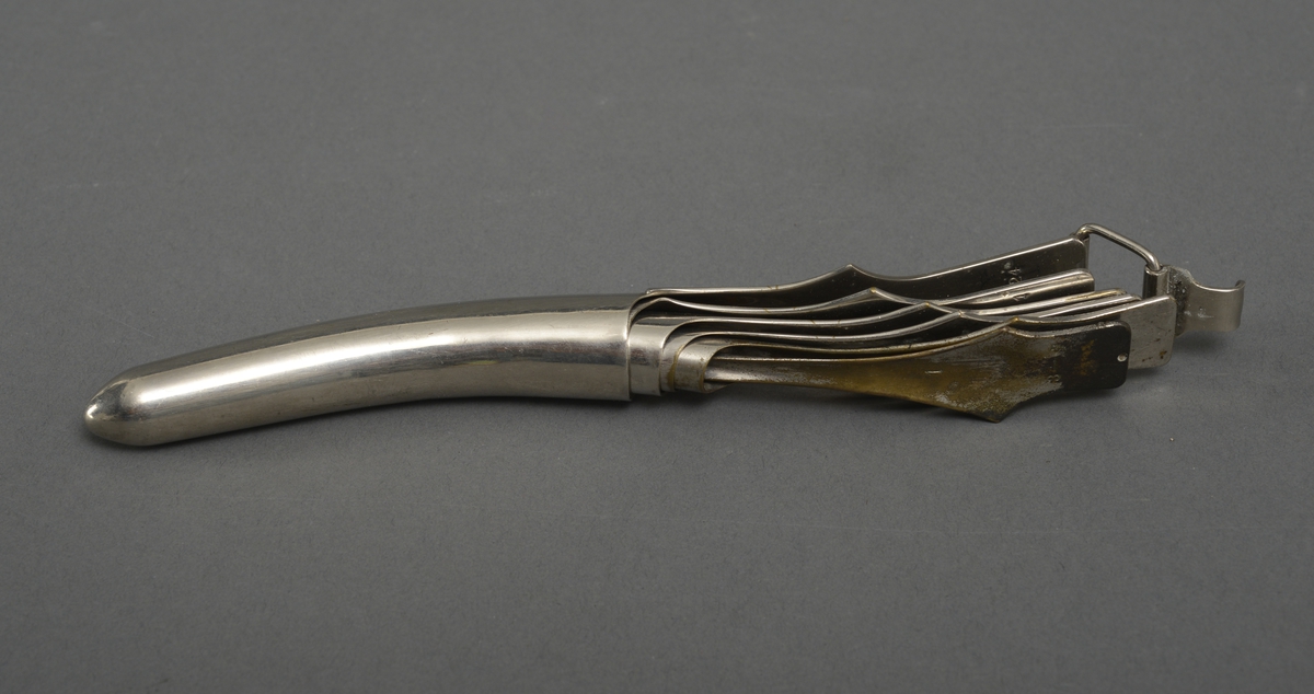 Lettere krummet metall instrument, avrundet spiss i ene enden og flat i andre ende. Stiftene kan etter størrelse plasseres inni hverandre.