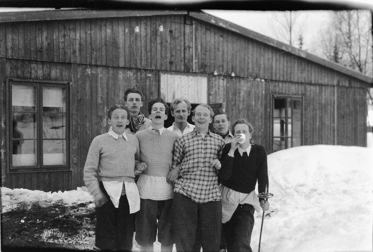 Syv menn foran et hus, nummer to fra venstre er Kåre Karlsen