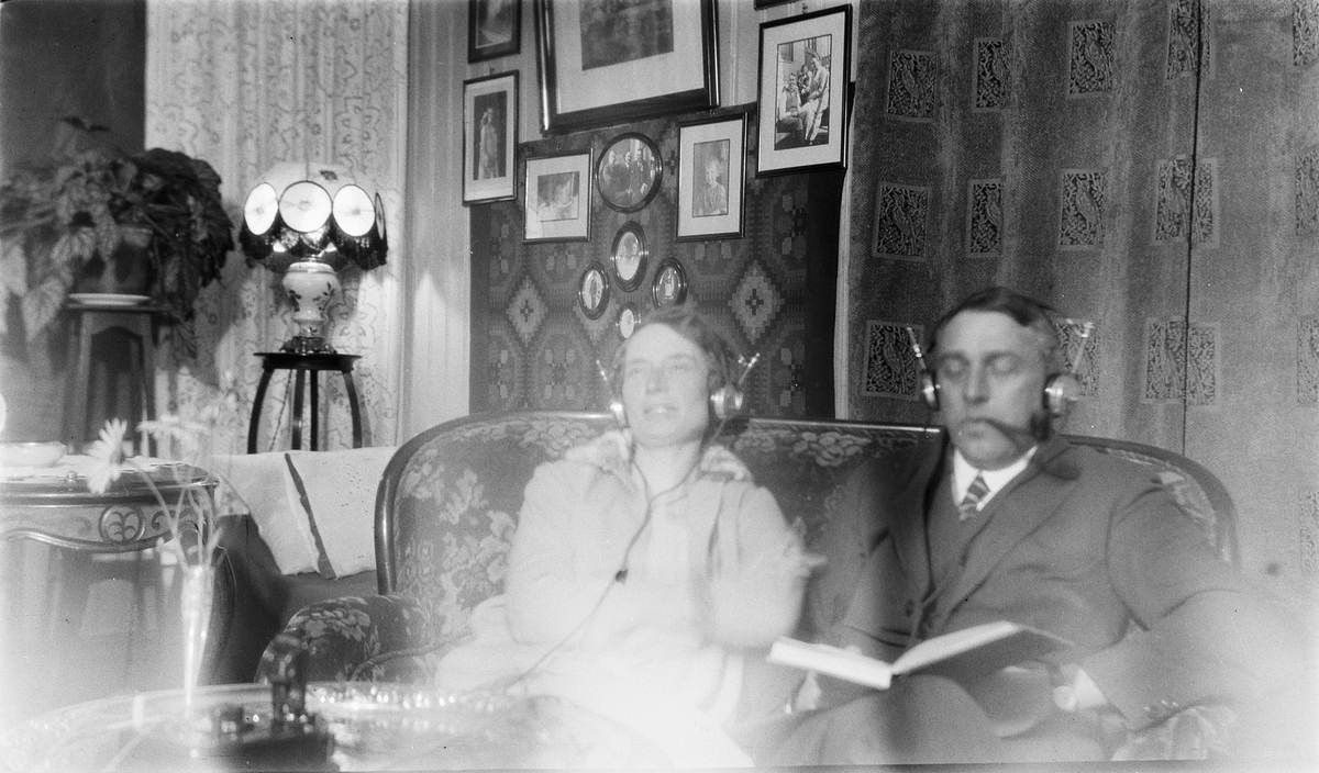 Interiør, stue. Ukjent kvinne og mann sitter i sofaen og lytter til krystallradio. 