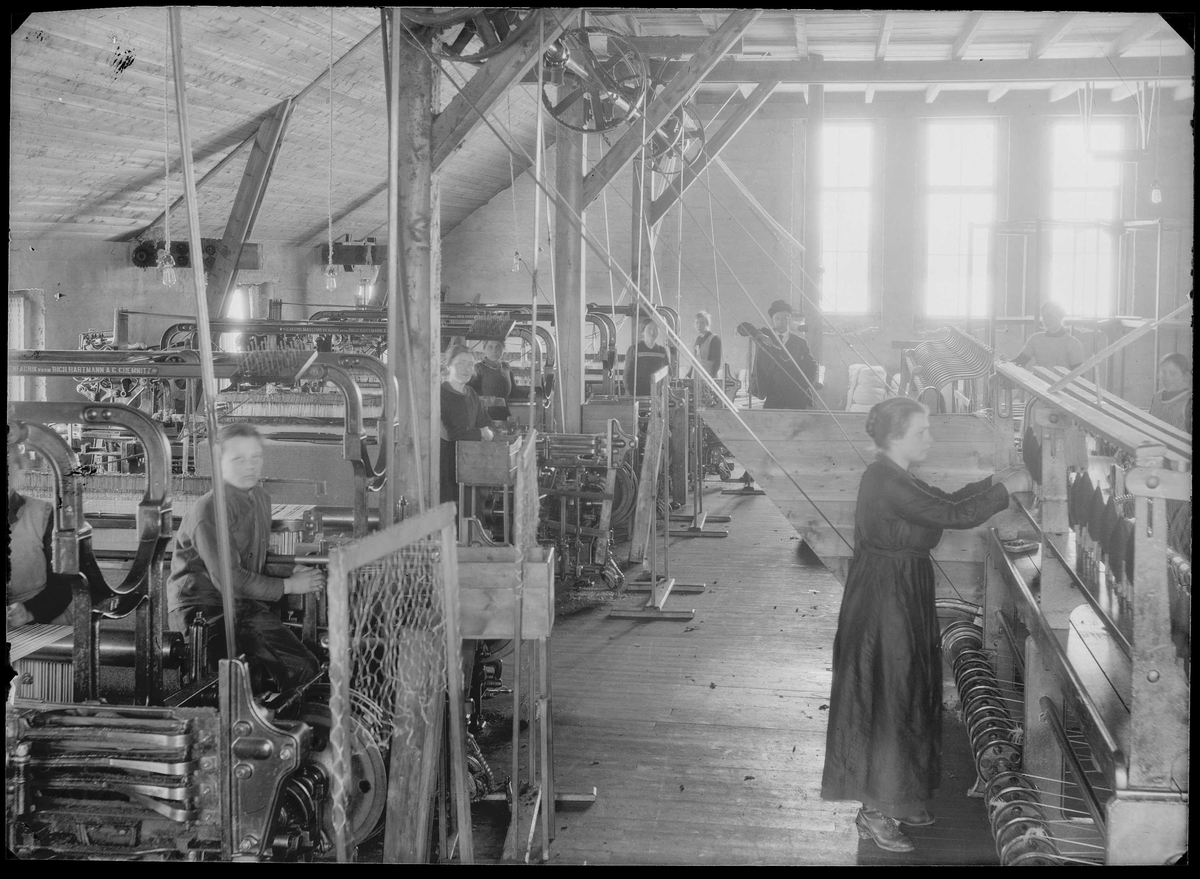 Interiørbilde fra produksjonshallen hos Brødrene Krog's Ullvarefabrikk, arbeidere ved maskinene.