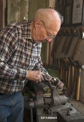 Smeden Oddbjørn Knudsen filer vedåpningen i ei merkeøks.  Fø