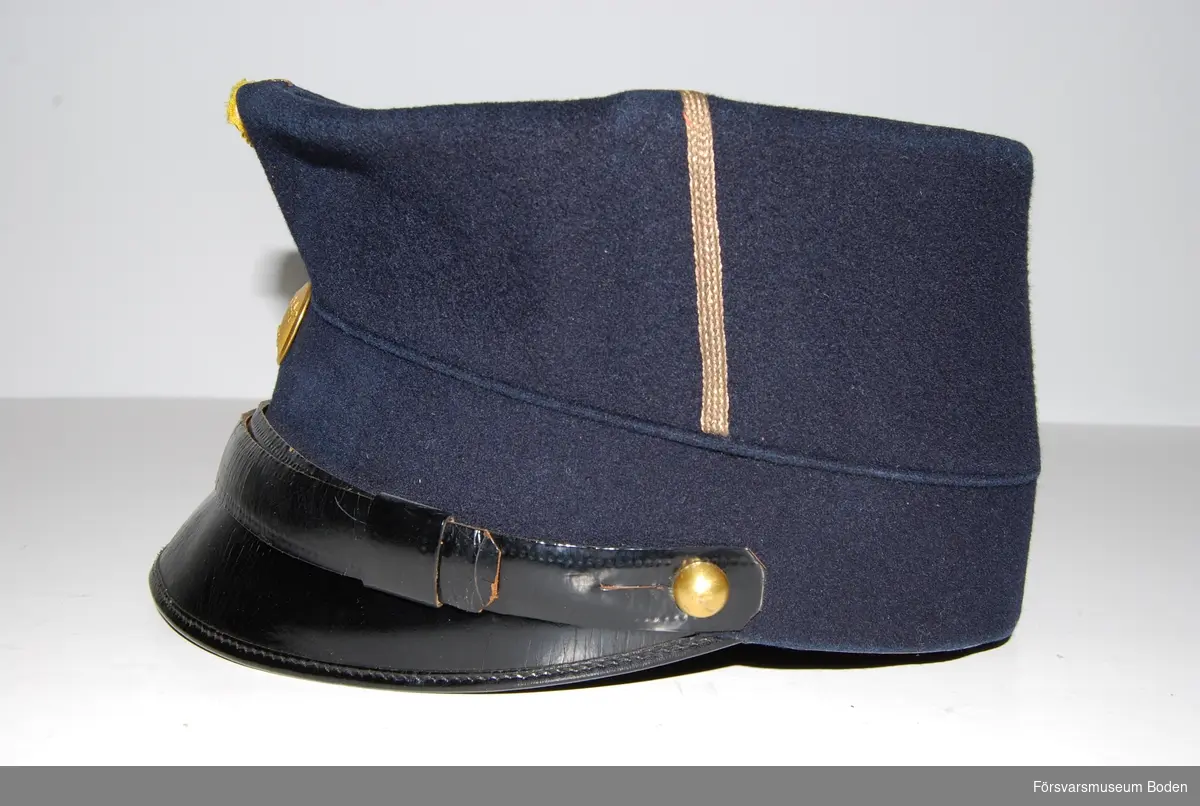Mörkblått kläde med en smal vertikal galon, betecknande sergeant efter1923. Hakrem av svart läder, fäst med kulknapp modell mindre i guld på sidorna. Framtill gul sidenkokard och mössknapp i guld  för underofficerare.