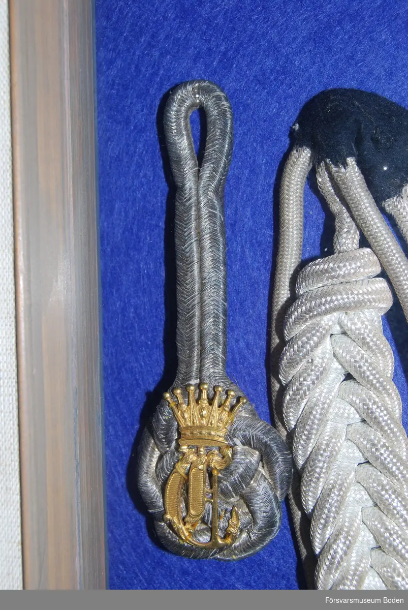 1 par med raka beläggningssnören i silver, nertill formade till valknut med prins Eugens namnchiffer i guld.