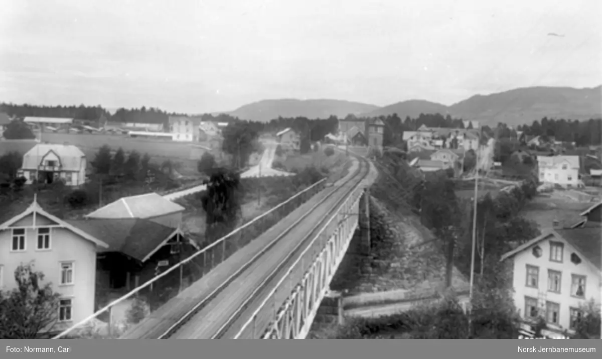 Moelv stasjon : oversiktsbilde med jernbanebrua og stasjonen i bakgrunnen