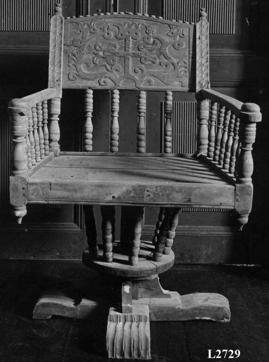 Armstol på kryss fot med mulighet for å snurres. Runeinnskrift skåret inn på ryggen. Dreid og skåret dekor.