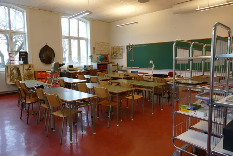 fotografi av klasserom fylt med skolepulter og stoler fra ca. 1970
