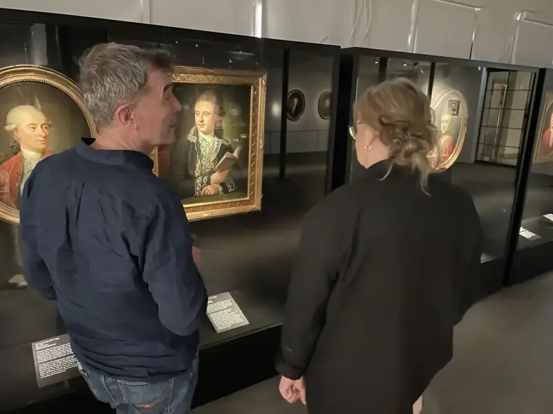 To besøkende betrakter portretter malt av Jens Juel i utstillingen på Bogstad Gård.